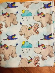 [Image: The fabric has Hippocorns on a blue background scattered about with birds and rain clouds with a sun peaking out. They appear to be playing across the fabric. The hippos have rainbow colored hair and horns and the birds also have rainbow wings.