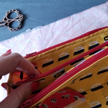 [Image; The yellow pockets of the sew together bag with red zippers.]